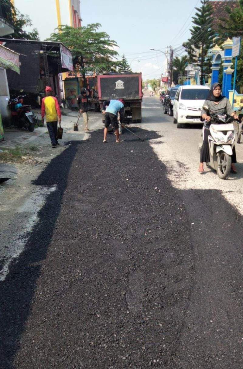 RATAKAN MATERIAL: Pekerja diturunkan untuk mengerjakan pemeliharaan di ruas jalan Sugio.  (GAMAL A/RDR.LMG)