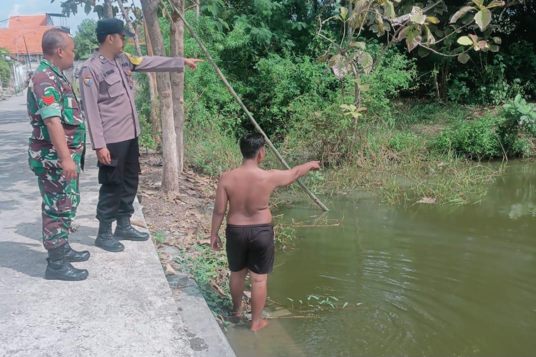 Petugas bersama warga menunjukkan lokasi telaga di Desa Bulutenger, Sekaran, Lamongan, tempat pelajar tenggelam saat libur sekolah usai pamit mancing.