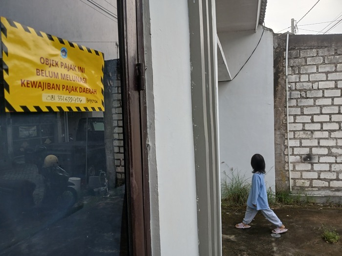 KEJAR PENDAPATAN: Salah satu rumah di salah satu perumahan yang belum membayar PBB ditempeli stiker pemberitahuan. (Anjar Dwi Pradipta/Radar Lamongan)