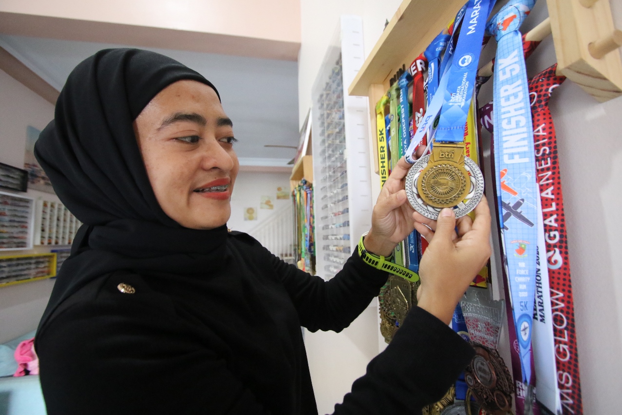 SUKA LARI SEJAK KECIL: Efi Neo Wati menunjukkan deretan medali dari berbagai event yang diperolehnya dari berlari. (ANJAR DWI PRADIPTA/RDR.LMG)
