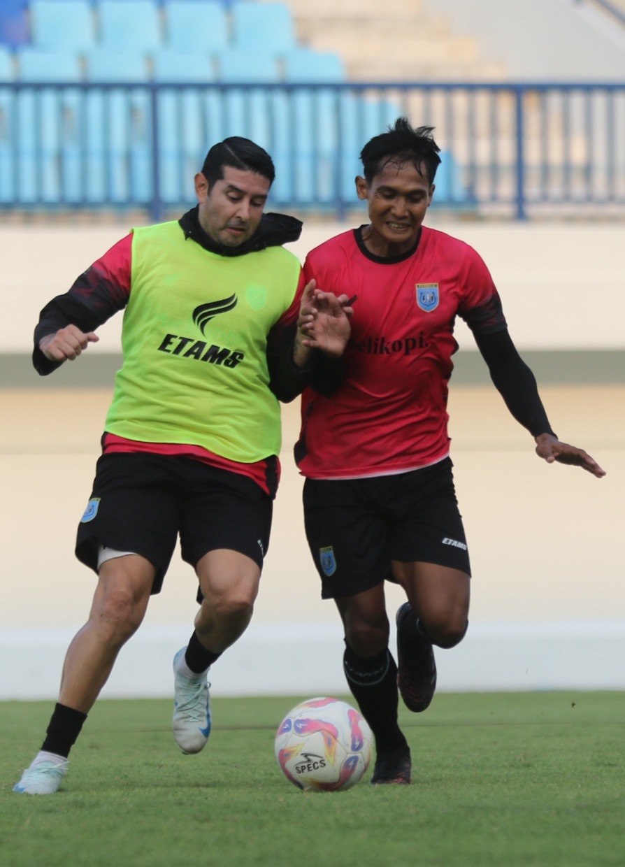 IKUT LATIHAN GAME: Gelandang naturalisasi, Esteban Viscarra, berebut bola dengan Hendro Siswanto saat latihan di Stadion Surajaya Lamongan. (ANJAR DWI PRADIPTA/RDR.LMG)
