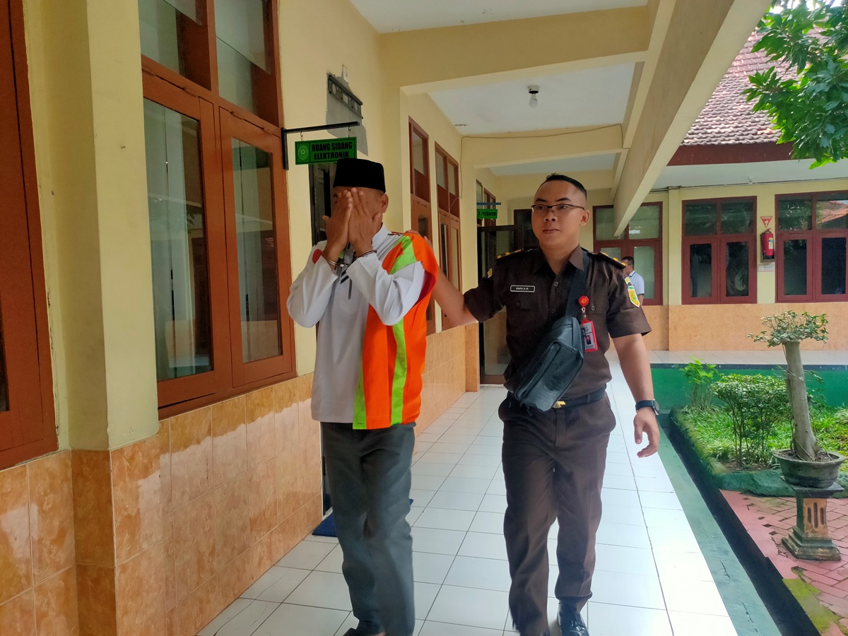 DITUNTUT 15 BULAN: Sukamdani menutupi wajahnya dengan tangan di Pengadilan Negeri Lamongan. Dia terjerat kasus pencurian uang warkop. (IST/RDR.LMG)