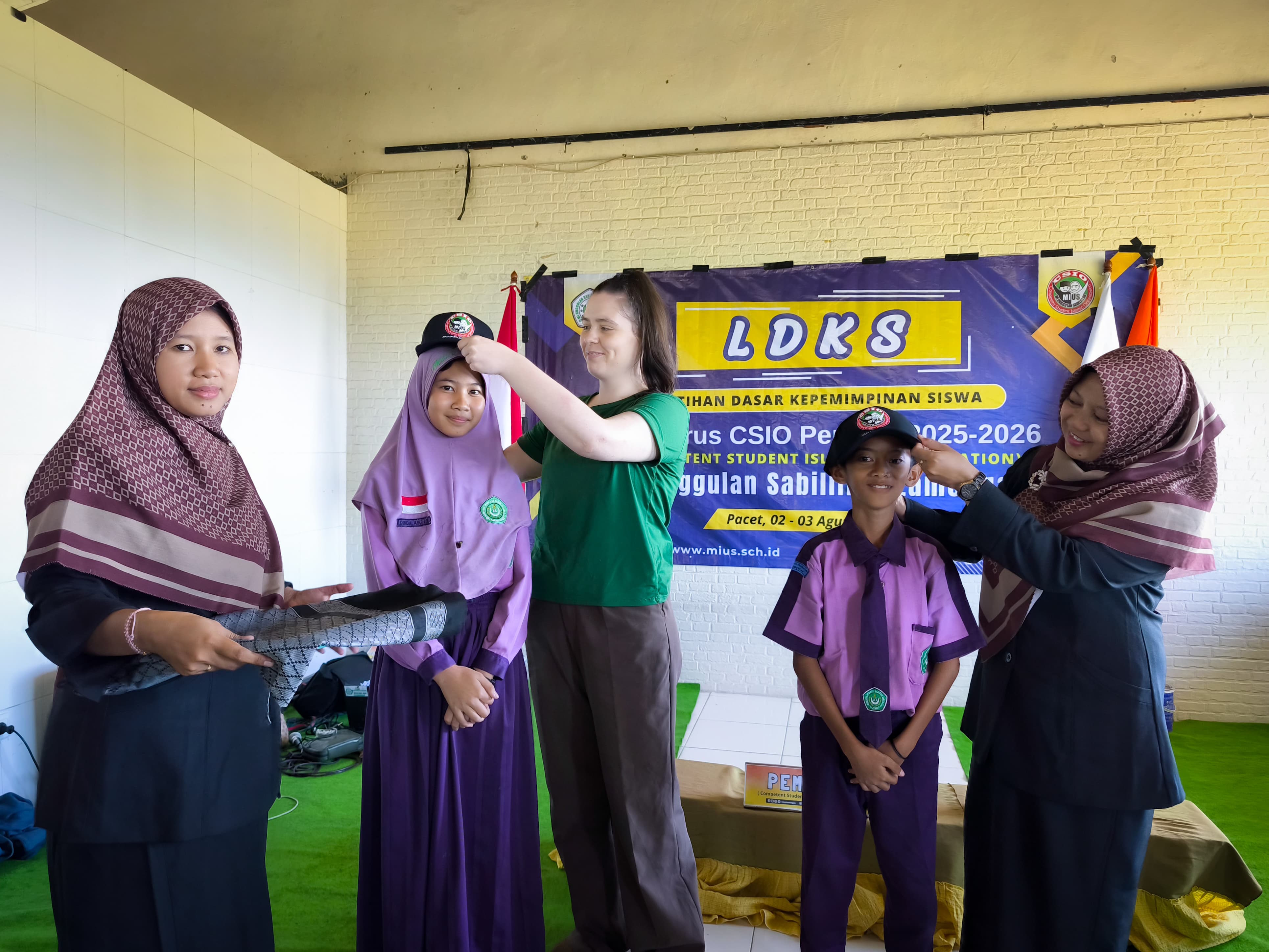 SUKES: Kepala MI Unggulan Sabilillah Lamongan, Ustadzah Uswatun Hasanah, MA, bersama guru tamu dari Canada, Ms. Joanie Martineau menyematkan topi pada kegiatan LDKS CSIO.