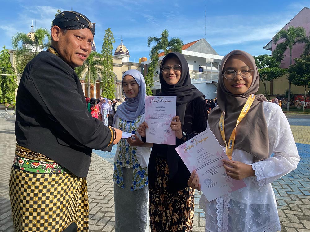 DIAPRESASI: Kepala SMAN 1 Lamongan Agus Hariyanto menyerahkan penghargaan kepada Natasya, Marsha, dan Auliyah. (IST/RDR.LMG)