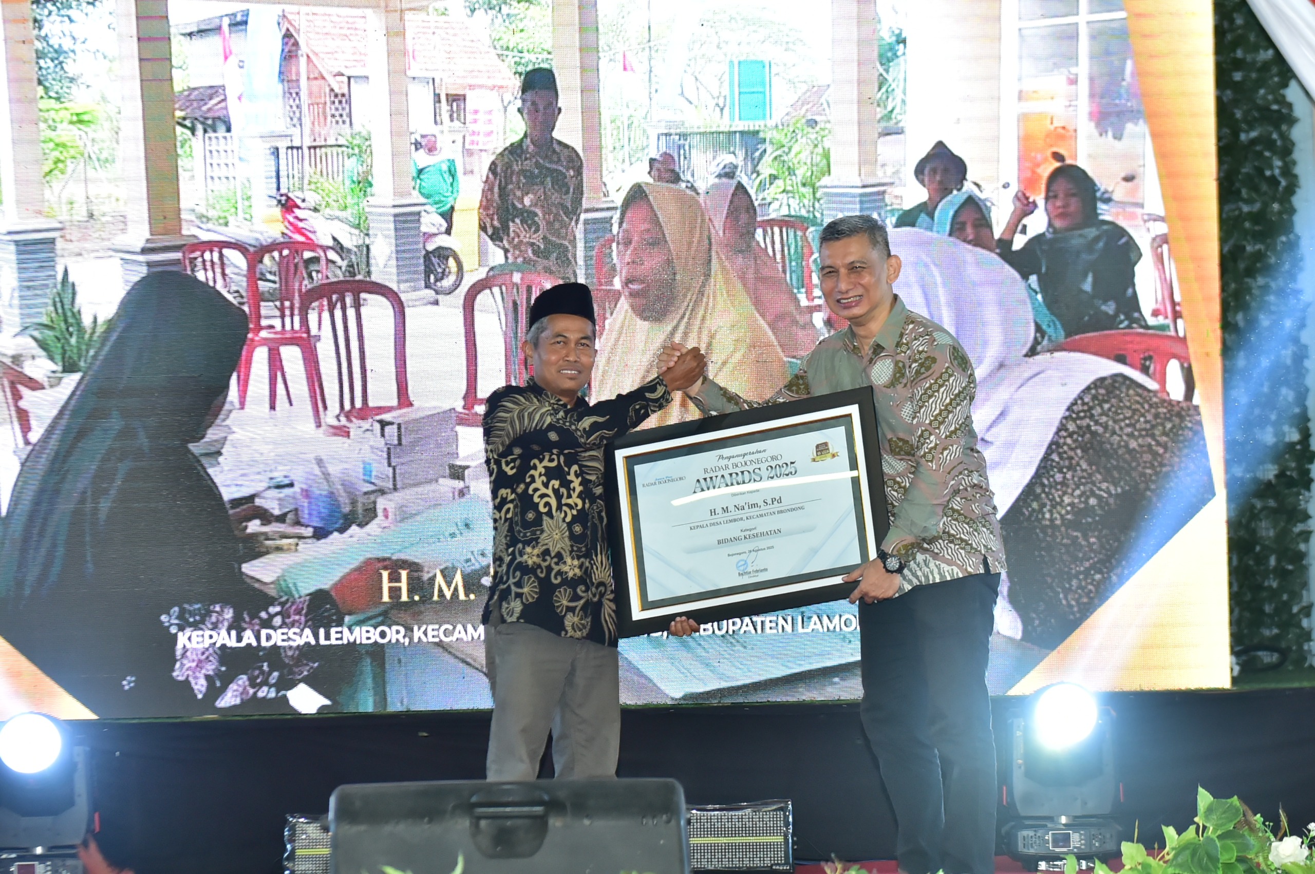 BERPRESTASI: Direktur Jawa Pos Radar Bojonegoro, Bachtiar Febrianto menyerahkan penghargaan kepada Kades Lembor, Kecamatan Brondong, H. M. Naim, S.Pd, sebagai Desa Inspiratif di bidang kesehatan.