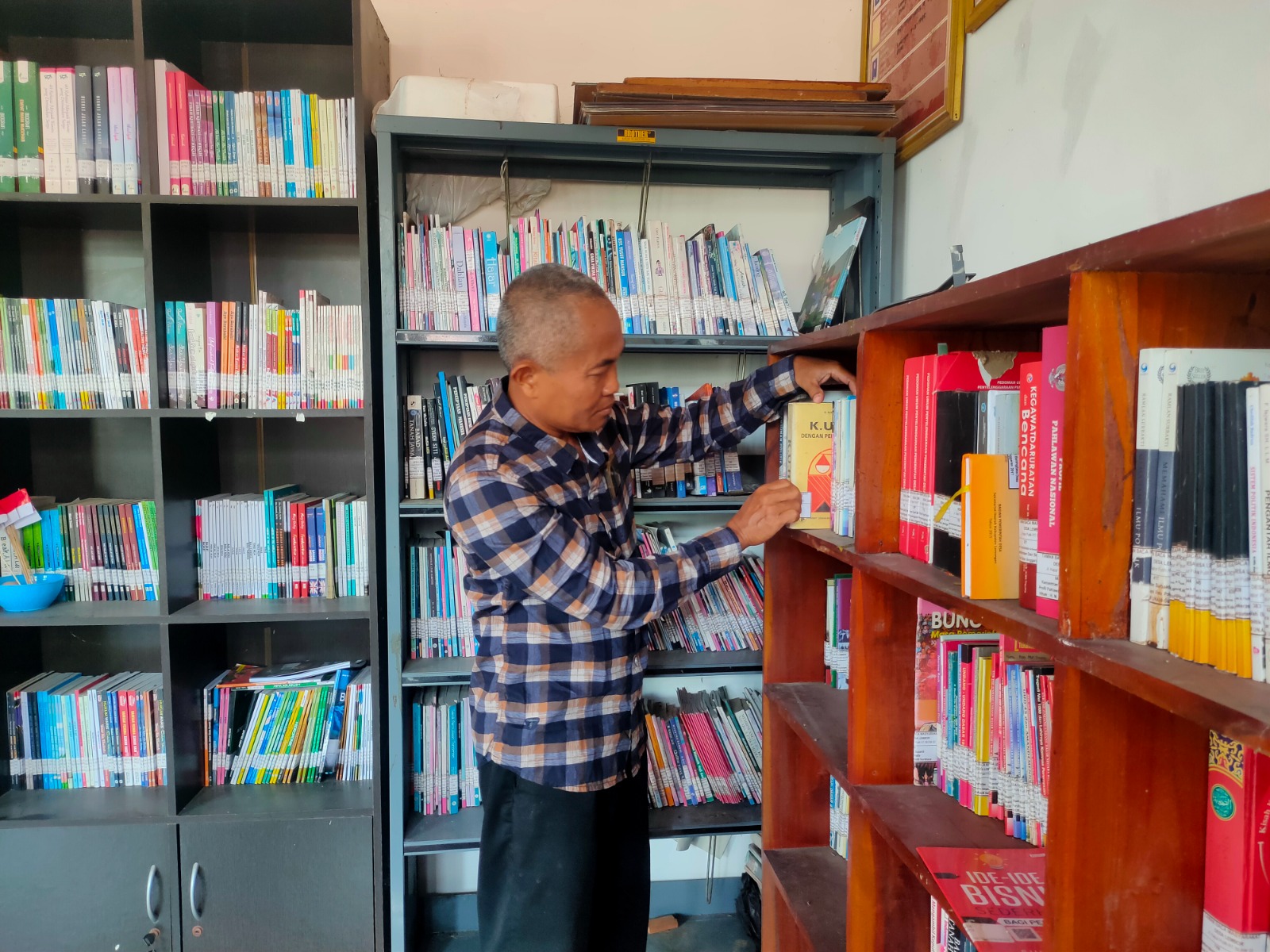 GELORAKAN LITERASI: Kades Lembor, Kecamatan Brondong, H. M. Naim, S.Pd saat mengecek perpustakaan desa.