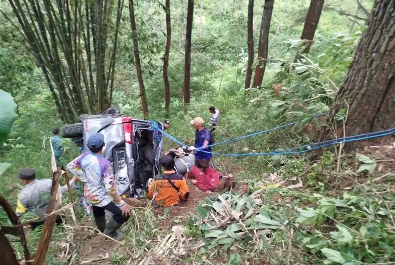 DIEVAKUASI: Petugas dibantu warga dan relawan berjibaku mengevakuasi mobil yang terjun ke jurang tepi Jalur Pacet-Cangar, Minggu (5/10). (martda/jprm)