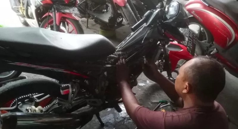 KURAS BENSIN: Mekanik sepeda motor di bengkel Jalan Empunala tampak mereparasi motor injeksi yang mbrebet usai isi bensin di pom bensin, Selasa (28/10). (dok.robi)