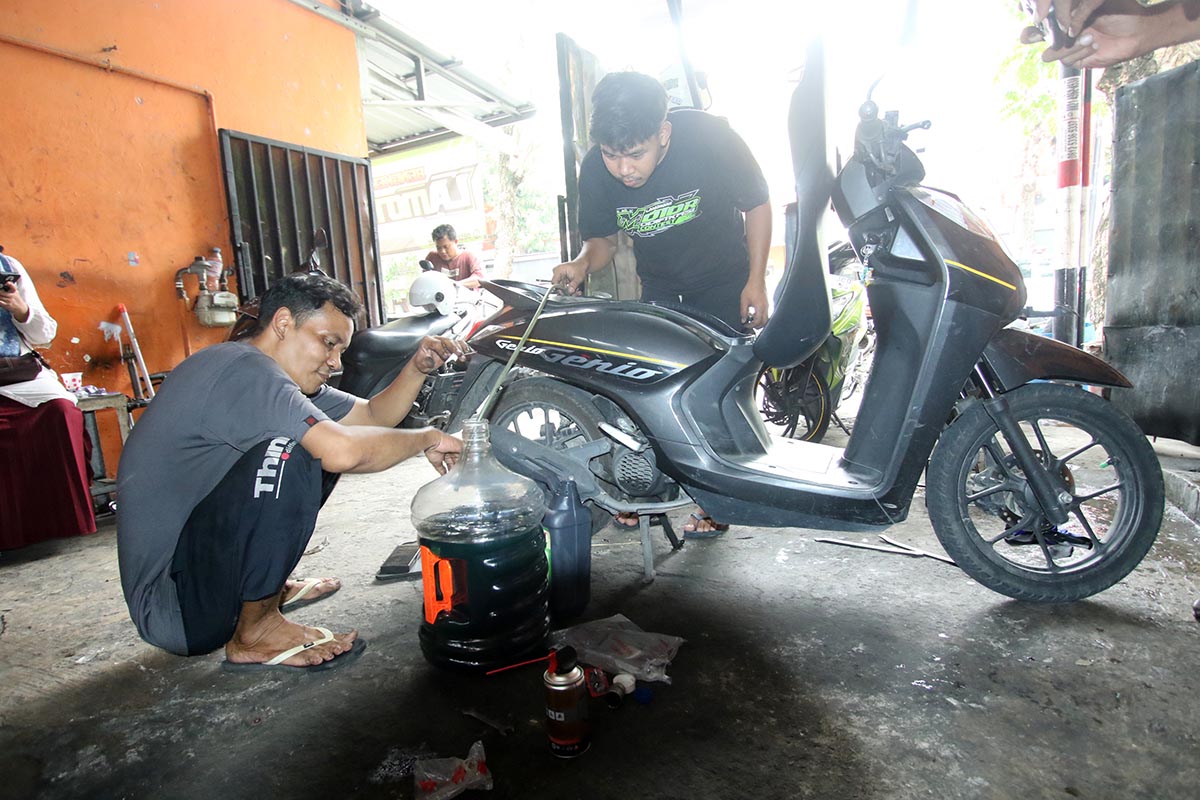 DIKURAS DULU: Pekerja di bengkel motor Jalan Lamongrejo Lamongan memasukkan Pertalite ke galon. Pertalite diduga menjadi penyebab motor brebet akhir &ndash; akhir ini. (ANJAR DWI PARDIPTA/RDR.LMG)