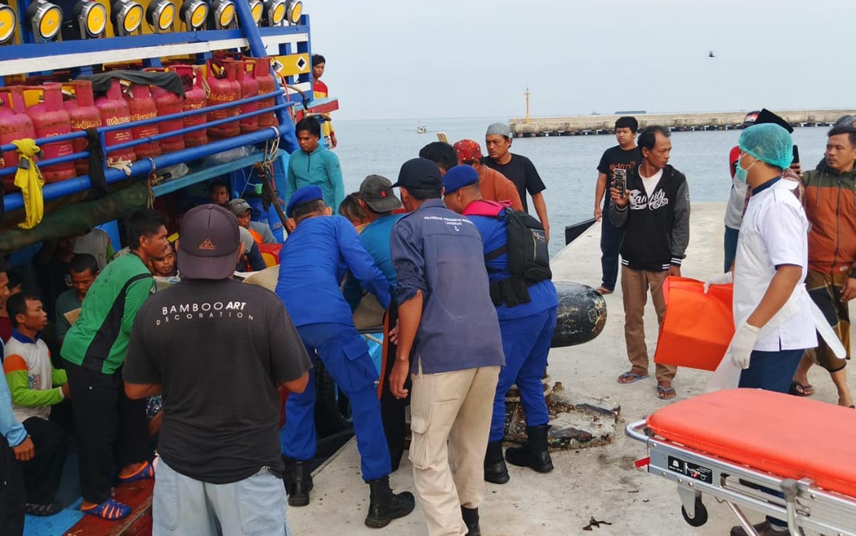 EVAKUASI: Warga dan petugas menurunkan jenazah ABK yang meninggal di perairan Bawean. (IST/RDR.LMG)