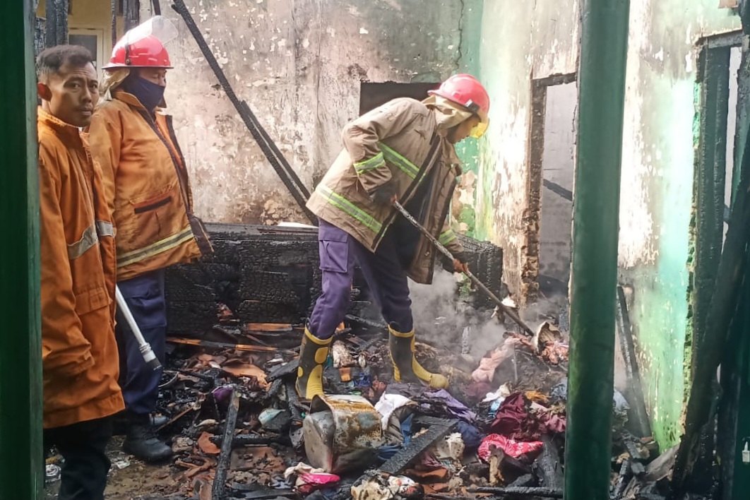 Petugas pemadam kebakaran menyisir puing-puing rumah warga di Kecamatan Sugio setelah api berhasil dipadamkan.