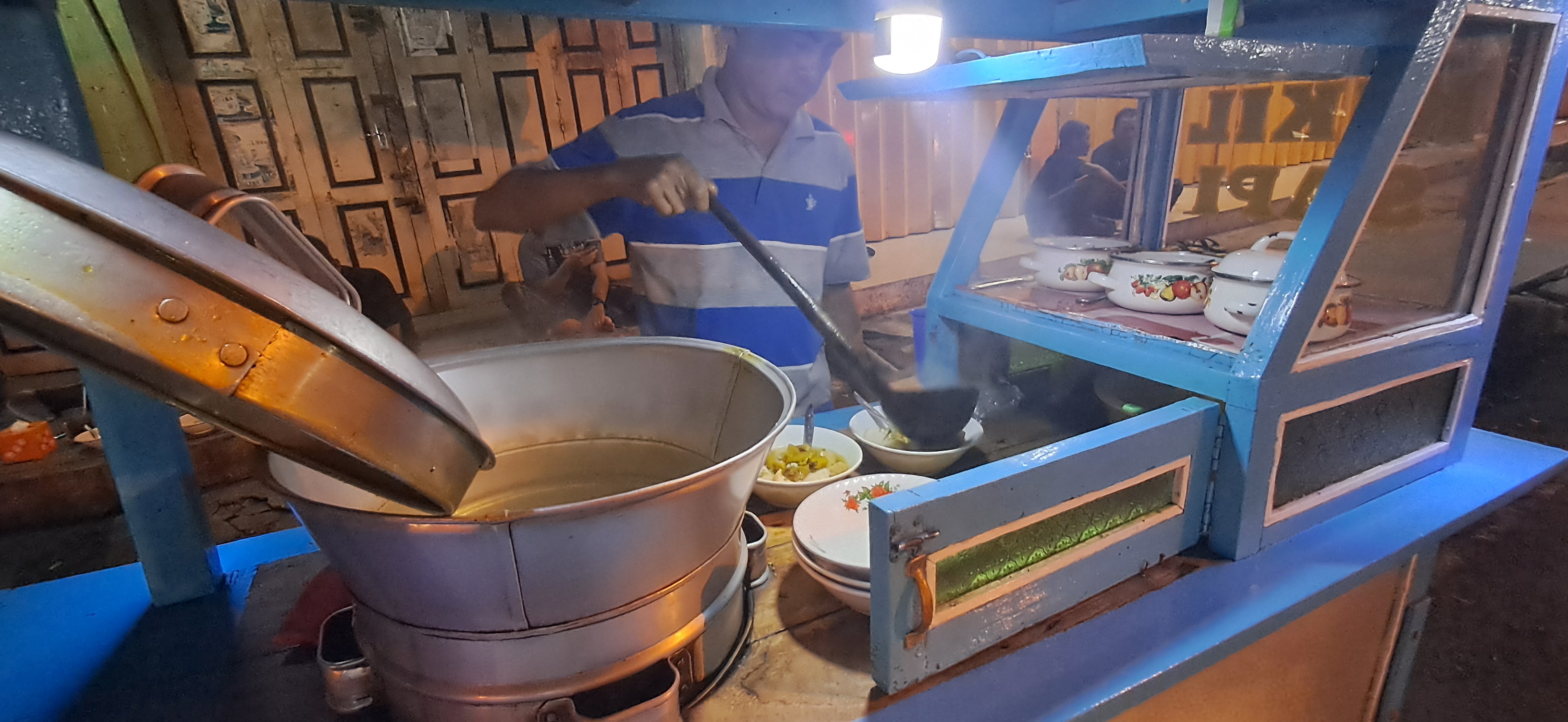 MANGKAL DI DEKAT MES PERSELA: Warno meladeni pembeli yang memesan lontong kikil sapi. Dia berjualan sejak sore.