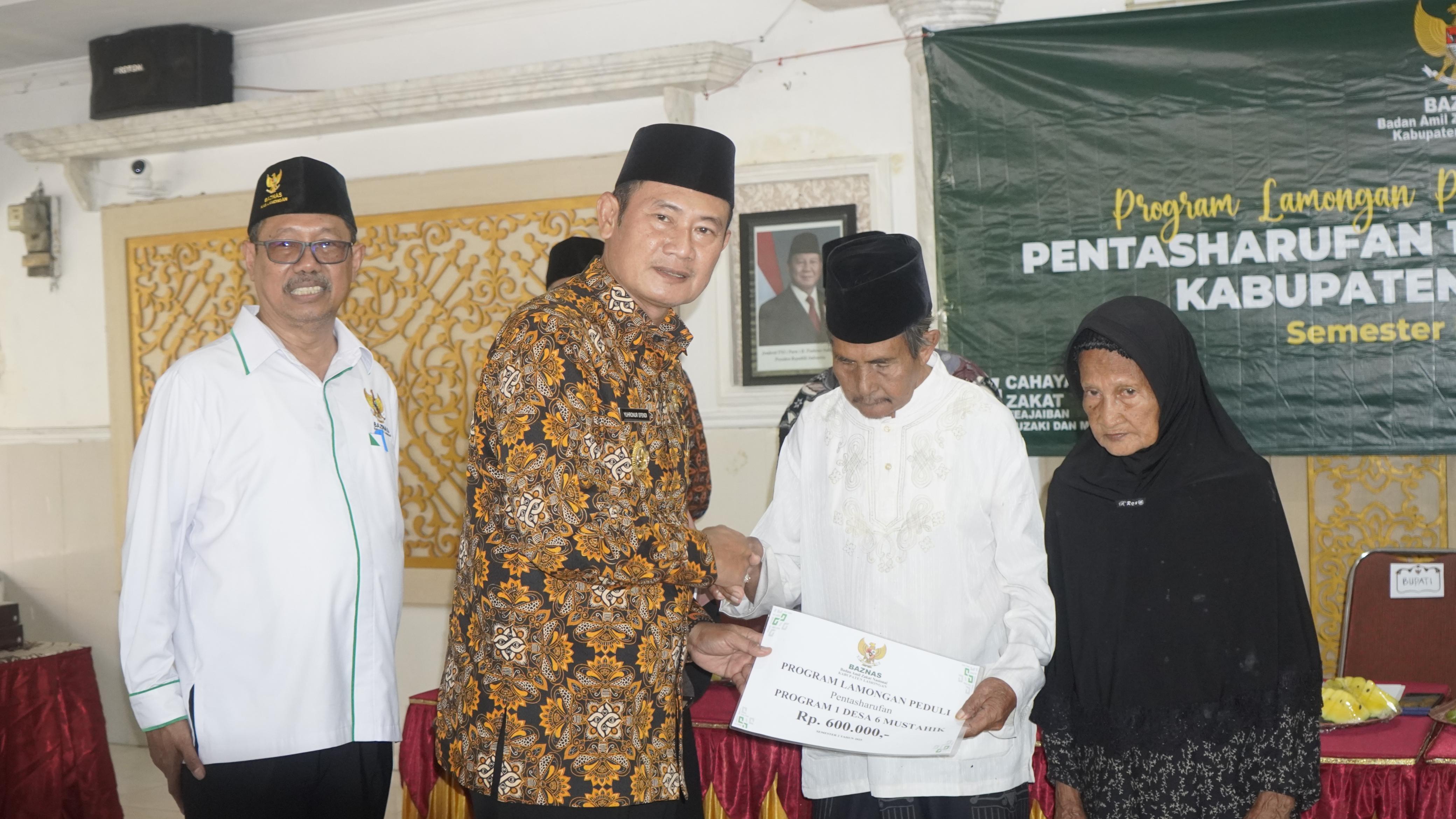 SIMBOLIS : Bupati Lamongan, Yuhronur Efendi, didampingi Ketua Baznas Kabupaten Lamongan Bambang Eko Muljono menyerahkan bantuan program 1 desa 6 mustahik