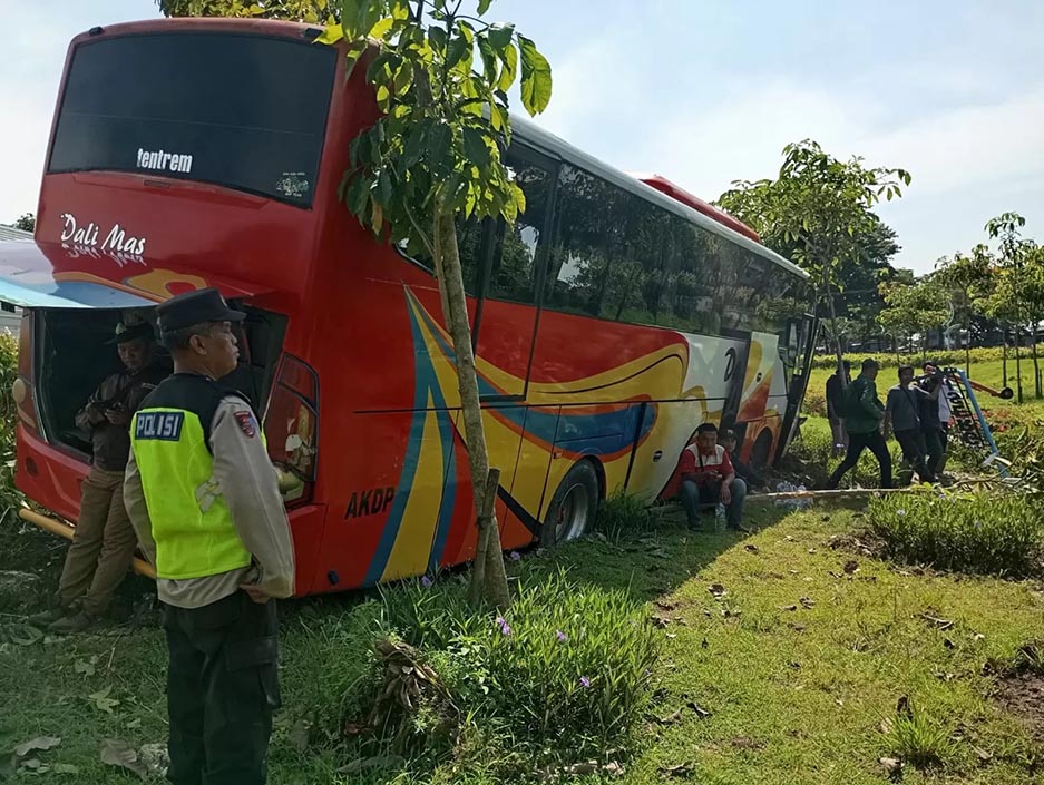 EVAKUASI: Anggota Polsek Duduksampeyan mengevakuasi penumpang dan mengamankan lokasi kecelakaan tunggal bus Dali Mas yang menabrak Taman Circle di Jalan Raya Desa Tambakrejo. (Ist/Radar Gresik)