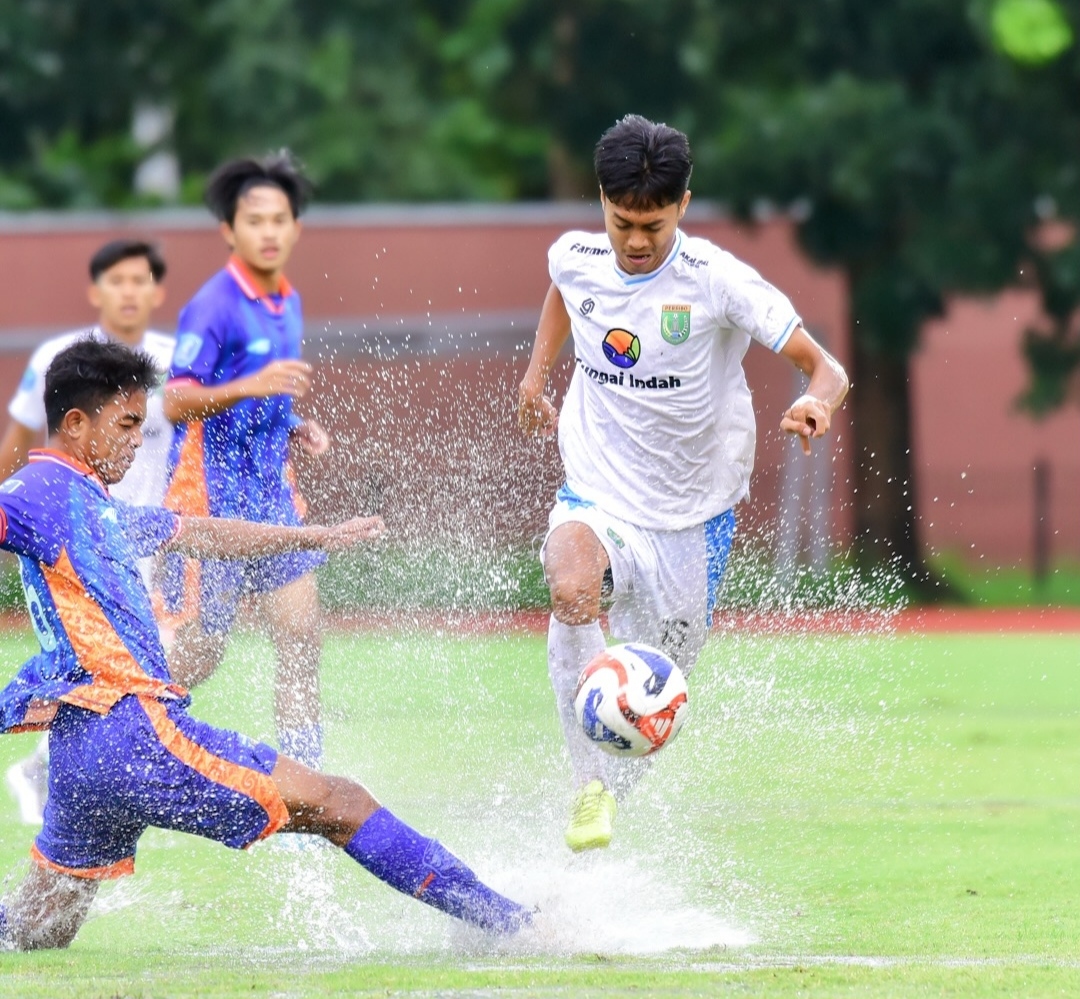 BOLA TERBANG : Pemain Peribo Bojonegoro membawa bola yang sulit dikendalikan karena lapangan tergenang air.