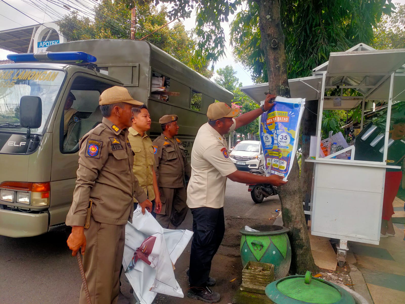 MELANGGAR: Petugas Satpol PP Lamongan membredel salah satu banner reklame yang dipaku di pohon.