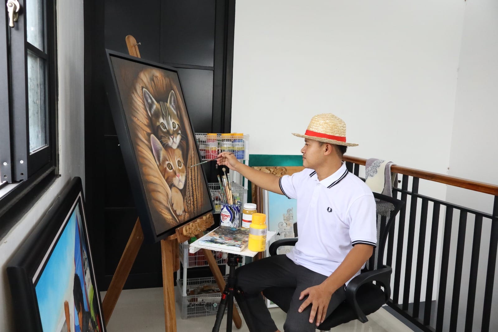 Wildan S saat menunjukkan sejumlah lukisan realis hasil karyanya.