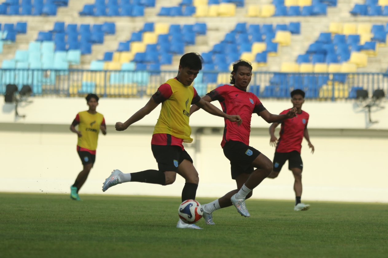 Adam Malik saat berduel dengan Yoga Pratama dalam sesi latihan di Stadion Surajaya Lamongan. 