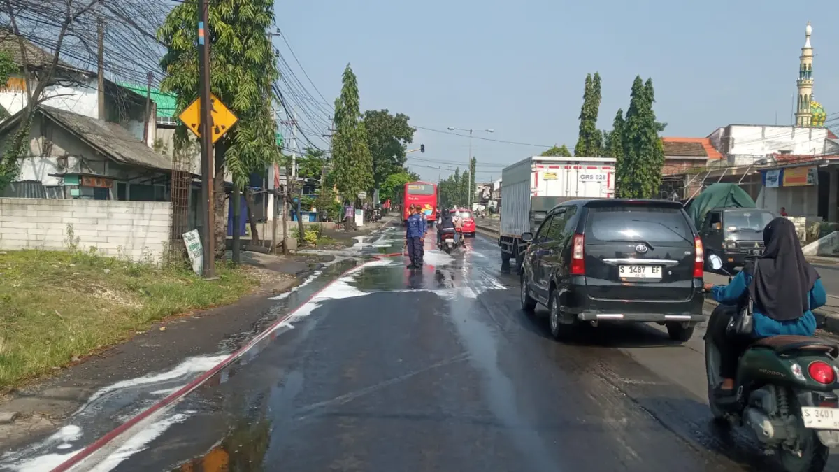 PELAN — PELAN: Kendaraan yang melintas di jalan poros Babat — Tuban, masuk Desa Plaosan, harus hati — hati saat ada luberan solar. (Istimewa/Radar Lamongan) 