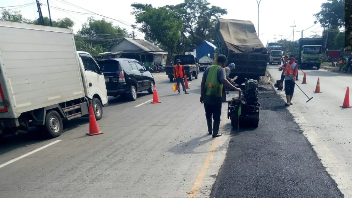 Petugas lapangan mengerjakan pengaspalan titik contraflow di jalan nasional. (GAMAL AYATULLAH/RADAR LAMONGAN)