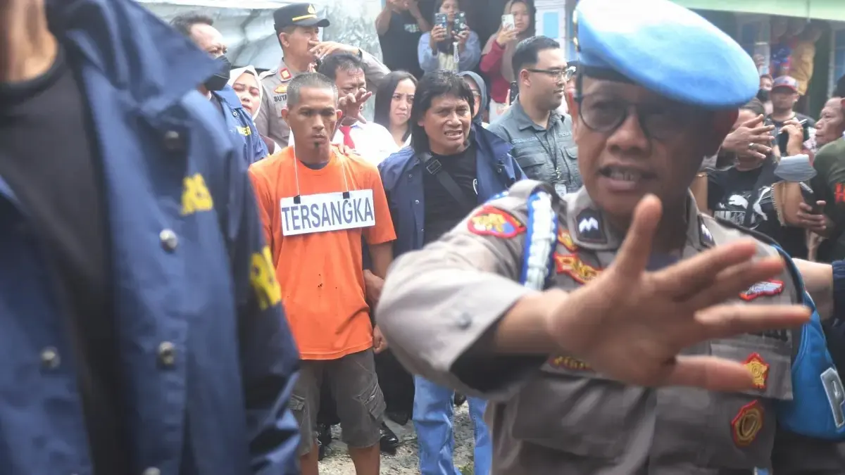 REKA ULANG: Tersangka Satuan saat melakukan rekonstruksi terkait kasus penganiayaan terhadap istri dan pembunuhan pada ibu mertuanya di Desa Sumbergirang, Kecamatan Puri, Kabupaten Mojokerto, kemarin (22/5). Petugas kepolisian dari Polsek Puri membantu mengamankan jalannya rekonstruksi yang menyita perhatian warga. (Sofan JPRM)