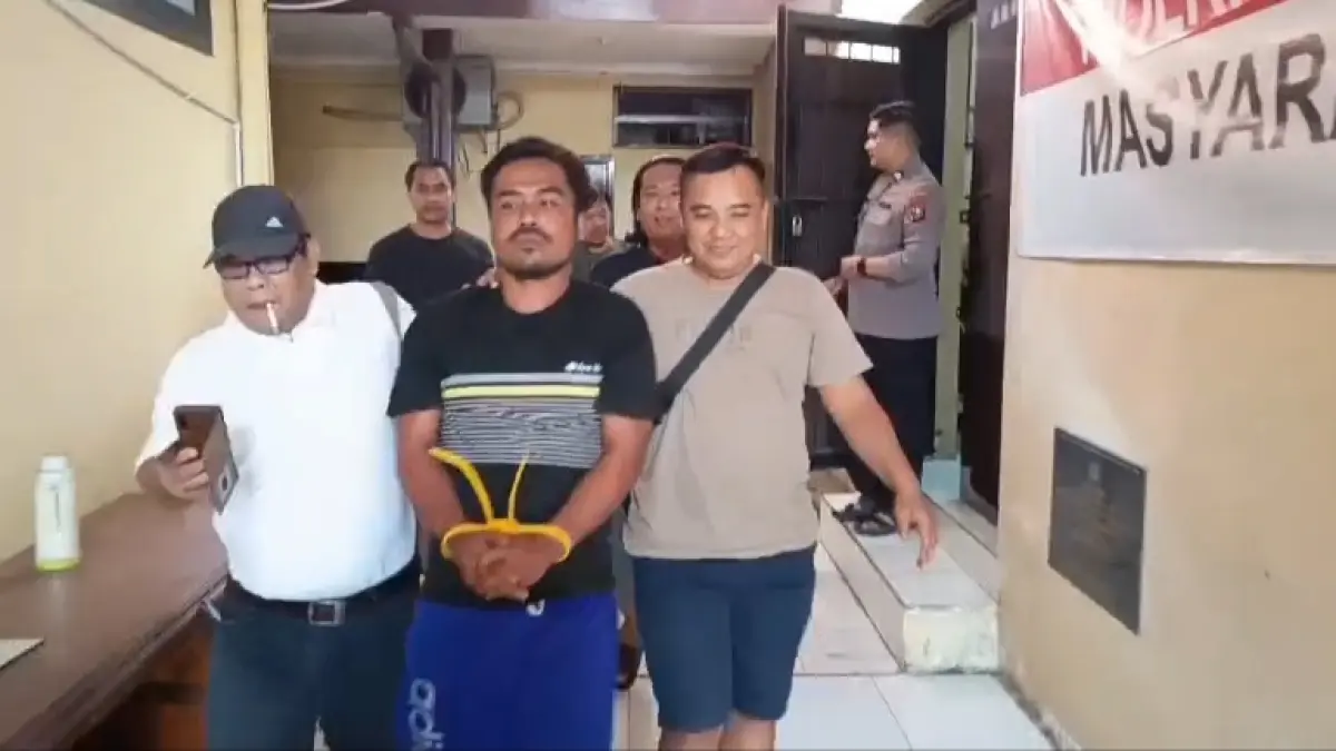 DiKAWAL PETUGAS: Kasmadi berjalan dengan tangan diborgol. Dia menjadi tersangka penganiayaan berujung kematian.&nbsp;(Gamal A/Radar Lamongan) 