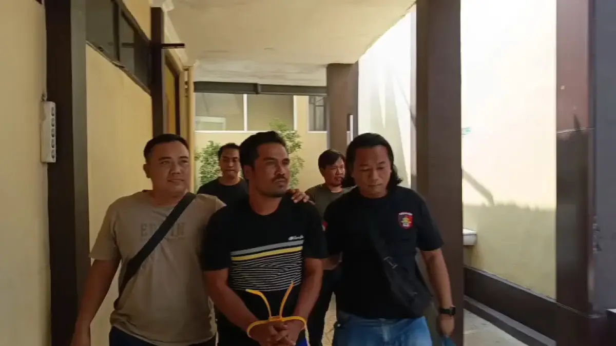 BAKAL DIPERIKSAKAN KONDISI KEJIWAAN: Kasmadi yang tangannya diborgol dan dikawal petugas setelah diamankan karena melakukan penganiayaan berujung kematian tetangganya.&nbsp;(Gamal A/Radar Lamongan) 