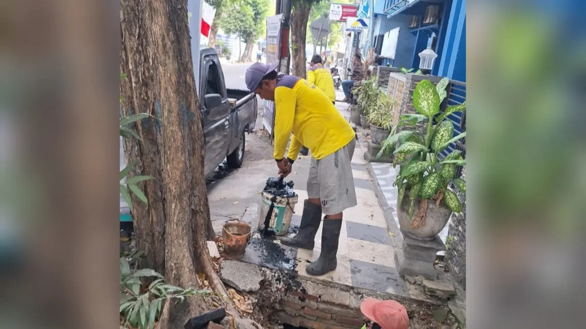 BERSIHKAN LUMPUR: Pekerja dari Dinas Bina Marga, Cipta Karya, dan Tata Ruang membersihkan lumpur yang ada di saluran air kawasan perkotaan. (Rika Ratmawati/Radar Lamongan) 