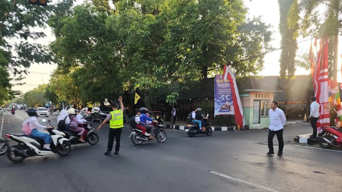 TAK HANYA PERSONEL SATLANTAS: Polisi yang membantu kendaran menyeberang di salah satu perempatan jalan. Program Commander Wish menjadi prioritas dengan melibatkan anggota lintas fungsi.&nbsp;(Gamal A/Radar Lamongan) 