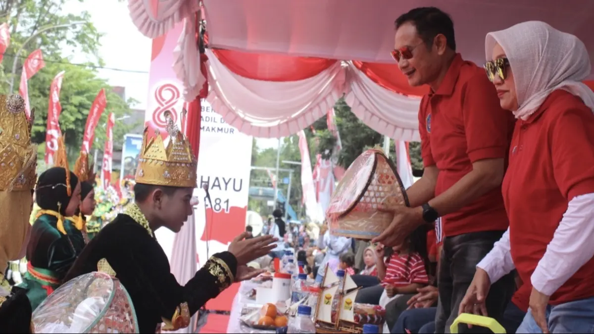 Siswa-siswi SMP Aplikatif As Sunniyyah Sunan Drajat Lamongan menyerahkan cendera mata untuk Bupati Lamongan Yuhronur Efendi dalam acara Karnaval Kemerdekaan Tahun 2026. (AHMAD ASIP/RADAR LAMONGAN)