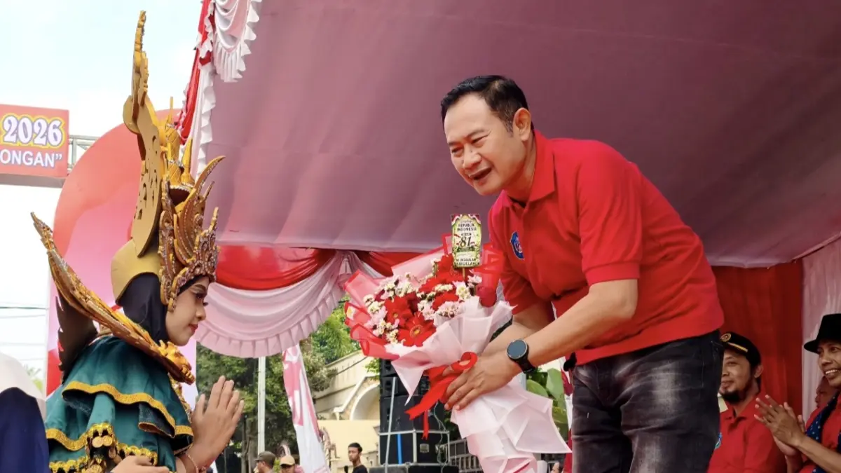 Siswa MIUS Lamongan menyerahkan cendera mata kepada Bupati Lamongan Yuhronur Efendi dalam Karnaval Kemerdekaan 2026. (AHMAD ASIP/RADAR LAMONGAN)
