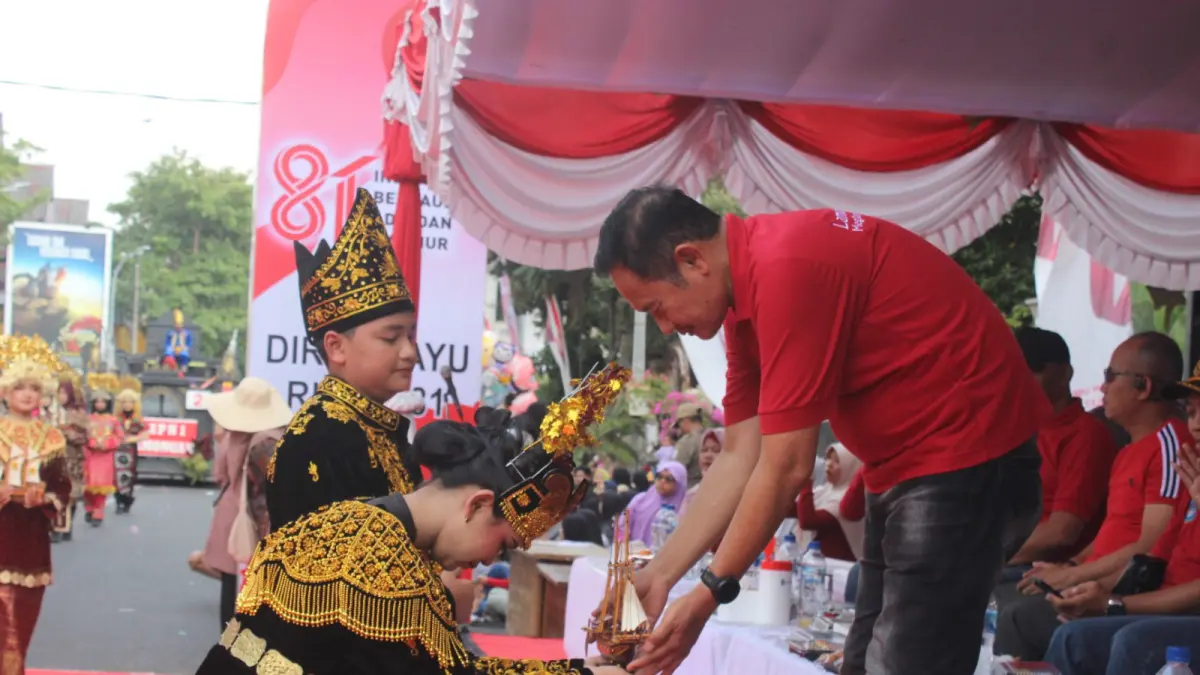 Siswa-siswi SMPN 1 Lamongan menyerahkan cendera mata kepada Bupati Lamongan Yuhronur Efendi dalam kegiatan Karnaval Kemerdekaan 2026.&nbsp;(AHMAD ASIP/RADAR LAMONGAN)
