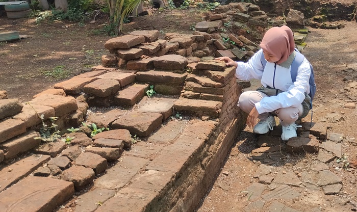 SIMBOL KERAJAAN: Pengunjung melihat bangunan berpola Surya Majapahit yang tersisa di Situs Klinterejo, di Desa Klinterejo, Kecamatan Sooko. (foto: Nadya Azzahra for Radar Majapahit)