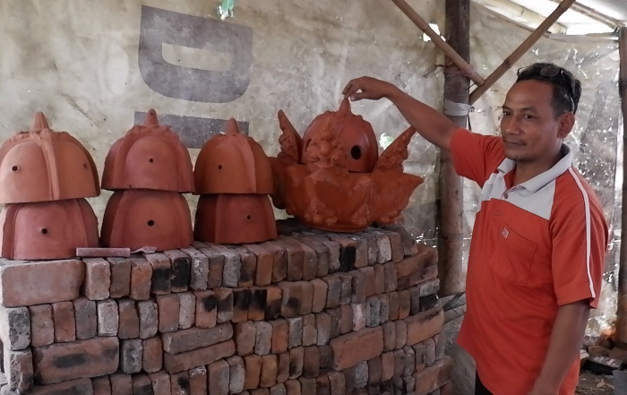 SENI: Lahuri menjelaskan makna yang terkandung dalam komponen terakota mahkota Majapahit, di Desa Jatipasar, Kecamatan Trowulan, Kabupaten Mojokerto. (foto: Misbakhul Ulum for Radar Majapahit)