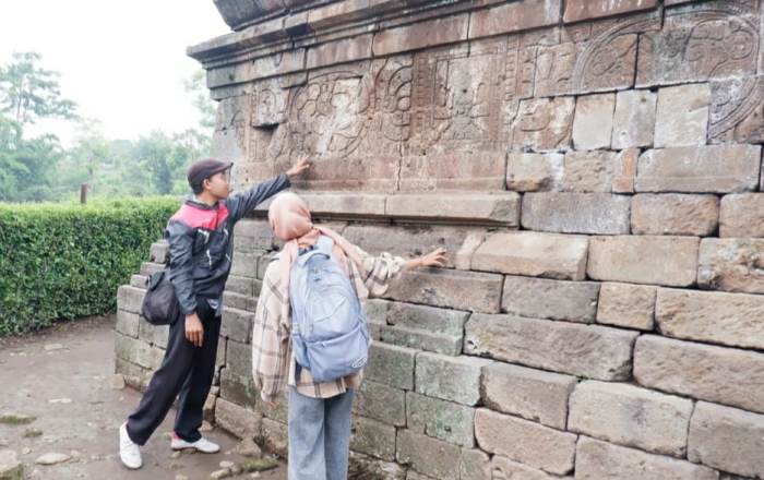MOTIF: Pengunjung mengamati relief dinding Candi Kesiman Tengah, Desa Kesiman Tengah, Kecamatan Pacet, Kabupaten Mojokerto. (foto: Misbakhul Ulum for Radar Majapahit)