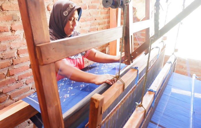 TRADISIONAL: Karyawan menenun produk kain tenun ikat menggunakan alat tenun tradisional, di Dusun/Desa Kedunguneng, Kecamatan Bangsal, Kabupaten Mojokerto. (foto: Misbakhul Ulum for Radar Majapahit)