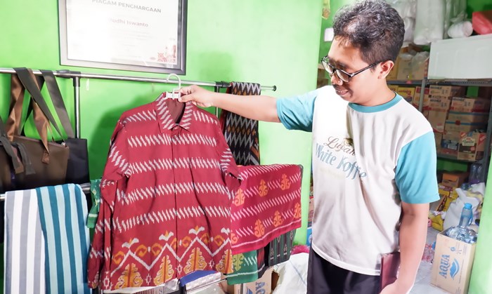 DIMINATI: Budi menunjukkan koleksi kemeja berbahan dasar kain tenun ikat motif Candi Wringin Lawang, di Dusun/Desa Kedunguneng, Kecamatan Bangsal. (foto: Misbakhul Ulum for Radar Majapahit)