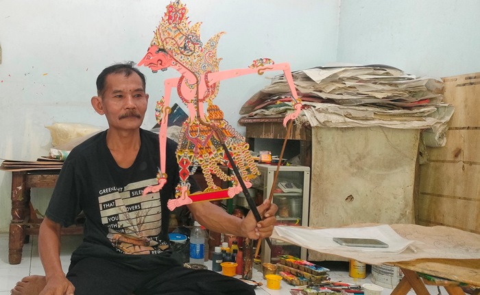 SENI: Hartono menunjukkan koleksi hasil kerajinan wayang kulit buatannya, di Dusun/Desa Bejijong, Kecamatan Trowulan, Kabupaten Mojokerto. (foto: Misbakhul Ulum for Radar Majapahit)