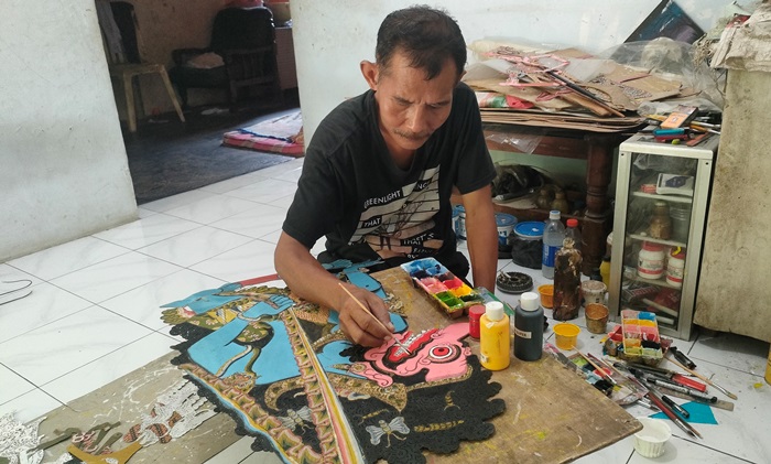 KEPIAWAIAN: Hartono melakukan proses pewarnaan wayang kulit di rumahnya, di  Dusun/Desa Bejijong, Kecamatan Trowulan, Kabupaten Mojokerto. (foto: Misbakhul Ulum for Radar Majapahit)