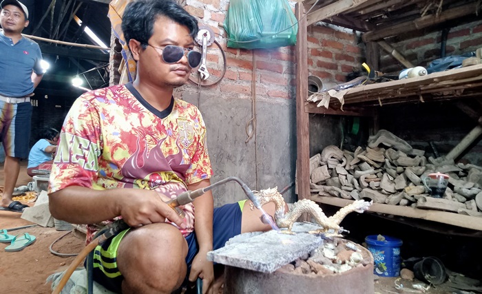 PENGELASAN: Proses penyatuan bagian miniatur naga hasil kerajinan kuningan di Dusun Kedungwulan, Desa Bejijong, Kecamatan Trowulan. (foto: Nadya Azzahra for Radar Majapahit)