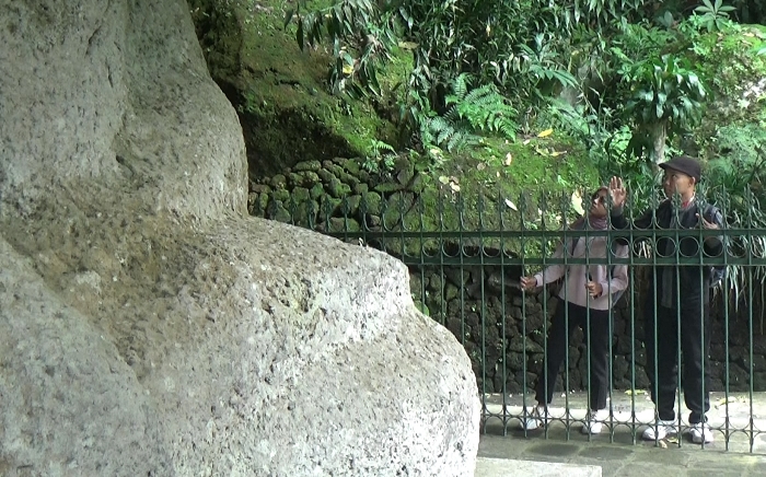 TAKJUB: Pengunjung mengamati Arca Buddha Akshobhya atau Reco Lanang, di Dusun Kemlaka, Desa/Kecamatan Trawas, Kabupaten Mojokerto. (foto: Misbakhul Ulum for Radar Majapahit)