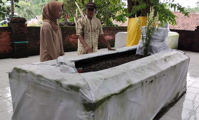 BERSEJARAH: Jupel Satuwi menceritakan sejarah makam Ki Ageng Resi Barat Wojo kepada pengunjung di Desa Menanggal, Kecamatan Mojosari, Kabupaten Mojokerto. (foto: Nadya Azzahra for Radar Majapahit)