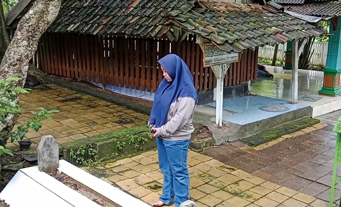 BERZIARAH: Peziarah sedang mengamati makam di sisi barat pintu masuk makam Syekh Abdul Ghofar, di Desa Bangeran, Kecamatan Dawarblandong. (foto: Bryan Noer for Radar Majapahit)