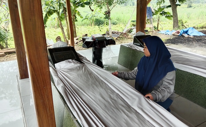 MENGAMATI: Peziarah sedang mengamati Makam Mbah Tulak sambil merapikan makam. (foto: Bryan Noer for Radar Majapahit).