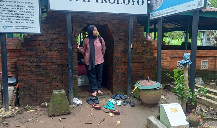 SAKRAL: Peziarah memerhatikan Makam Pangeran Noto Suryo di Makam Tujuh Troloyo, di Dusun Sidodadi, Desa Sentonorejo, Kecamatan Trowulan, Kabupaten Mojokerto. (Foto Laila Ramadani for Radar Majapahit)
