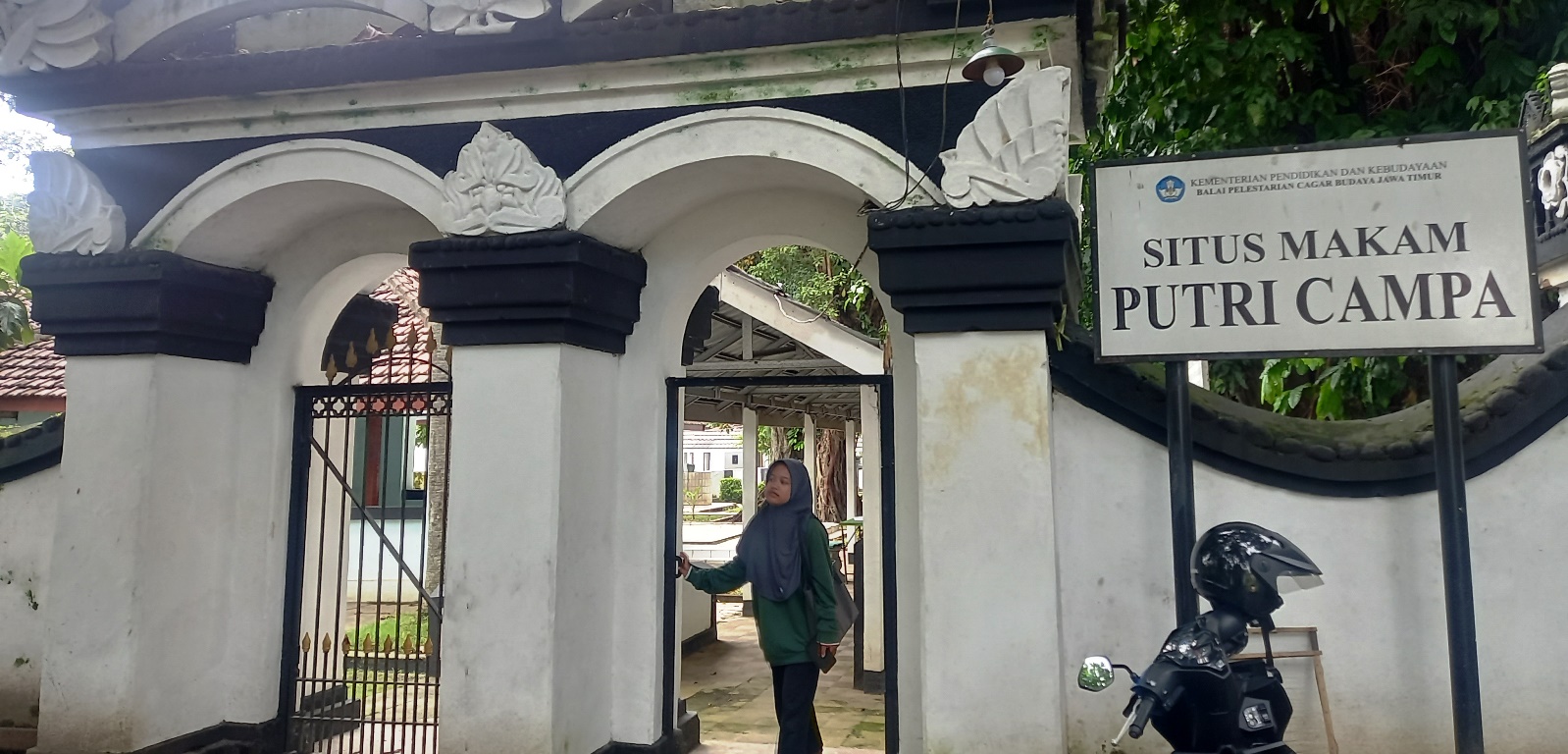 UNIK: Pengunjung mengamati bagian depan pintu masuk situs Putri Campa yang terdapat ukiran bunga cempaka di bagian pilar makam di Dusun Unggahan, Desa/Kecamatan Trowulan, Kabupaten Mojokerto.