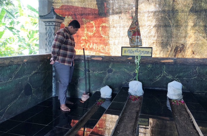 MENGAMATI: Peziarah sedang memperhatikan nisan yang dibungkus kain putih di area Makam Mbah Serut.