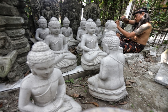 TEKUN: Perajin batu di Trowulan, Mojokerto, tengah memahat patung. (Sofan Kurniawan/JPRM)