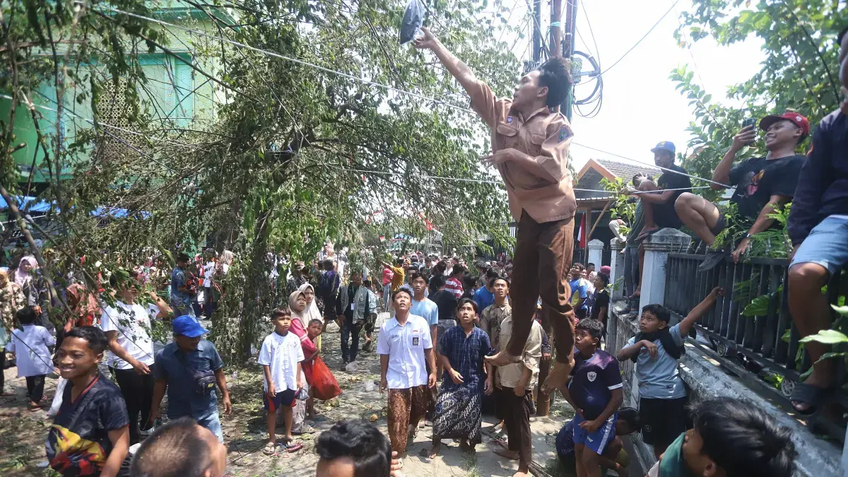 LESTARIKAN TRADISI: Seorang siswa melompat meraih barang yang digantungkan di pohon kersen dalam tradisi keresan di Dusun Mengelo, Desa/Kecamatan Sooko, Kabupaten Mojokerto, Selasa (25/8).&nbsp; (Foto:JPRM/Sofan Kurniawan)