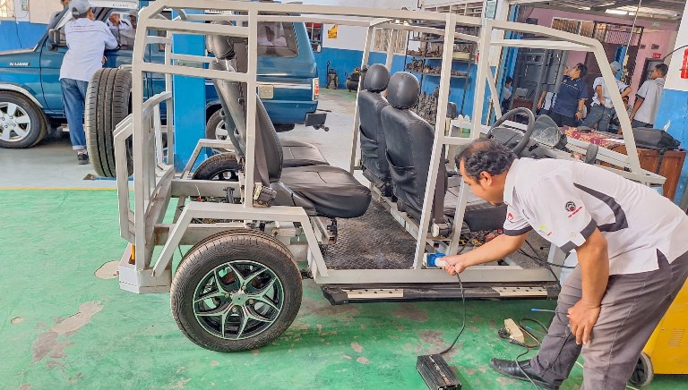 PENGISIAN DAYA: Guru mata pelajaran kelistrikan di SMKN 1 Kota Mojokerto Arif Maksani menancapkan charger dalam proses pengisian daya mobil listrik.